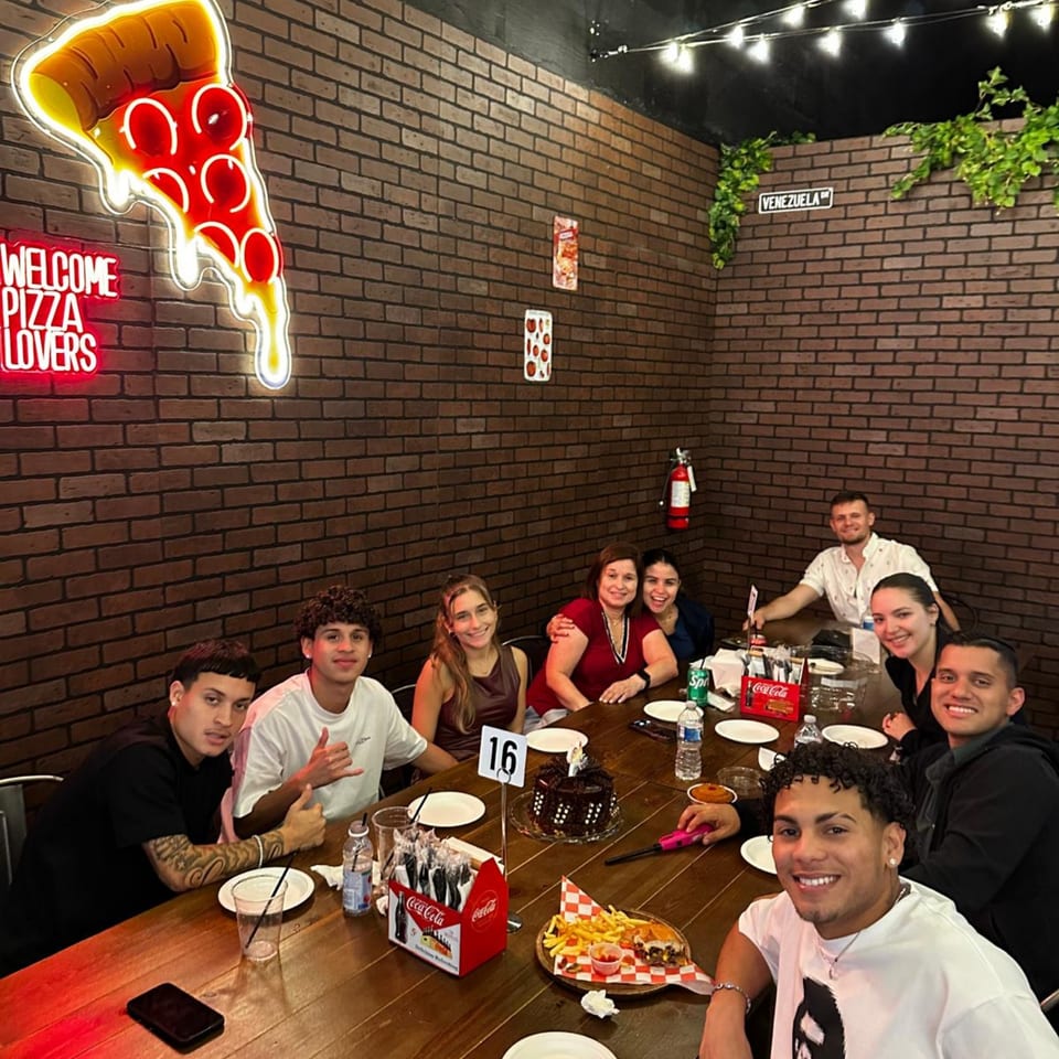 A group of people celebrating at a long wooden table in Pia's Not Just Pizza.