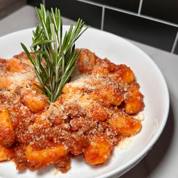 Pia's Not Just Pizza's gnocchi with red sauce, parmesan cheese, and a rosemary sprig.